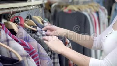 女人在购物中心挑选衣服。 购物。 一个女人`手从商店的衣架上取下衣服。 五彩缤纷